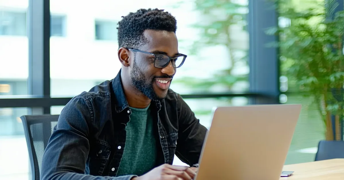 A new employee at a laptop looking confident and self-sufficient on their first day, reviewing internal documentation